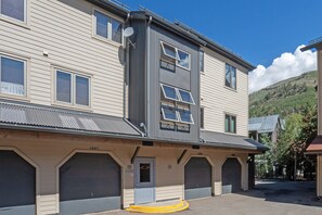 A multi-story building with a garage entrance, a satellite dish, and a view of a mountainous landscape. - Sunset Vista 3 Bedroom Condo (Telluride)