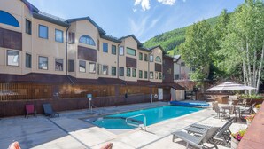 Um hotel com piscina, área de estar externa e vista para uma montanha arborizada.