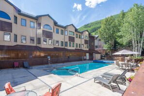 A hotel with a swimming pool, outdoor seating, and a view of a forested mountain. - Sunset Vista 3 Bedroom Condo (Telluride)