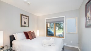 Quarto moderno com uma cama grande, janela com vista para o exterior e um quadro na parede.