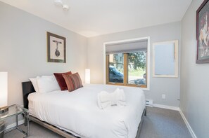 A modern bedroom with a large bed, a window with a view of the outside, and a framed picture on the wall. - Sunset Vista 3 Bedroom Condo (Telluride)