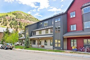 Un immeuble à plusieurs étages doté d’un porche couvert et surplombant un paysage montagneux.
