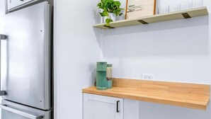 A kitchen with a stainless steel refrigerator, a wooden countertop, and a shelf with a plant and a coffee maker. - Big Island Kahaluu Surf Boutique #4 2 Bedroom Apts (Kailua-Kona)