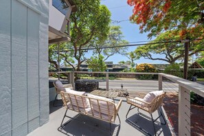 An outdoor seating area with wicker furniture and a stone fire pit. - Big Island Kahaluu Surf Boutique #4 2 Bedroom Apts (Kailua-Kona)
