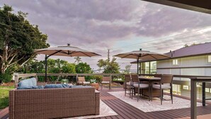 A deck with outdoor furniture, including a sofa and chairs, under umbrellas. - Big Island Kahaluu Surf Boutique #4 2 Bedroom Apts (Kailua-Kona)
