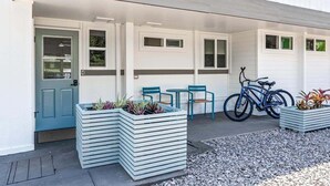A modern building with a flat roof, a blue door, and a bicycle parked outside. - Big Island Kahaluu Surf Boutique #4 2 Bedroom Apts (Kailua-Kona)