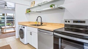 A modern kitchen with a dishwasher, oven, and a sink. There are white cabinets and a wooden countertop. - Big Island Kahaluu Surf Boutique #4 2 Bedroom Apts (Kailua-Kona)