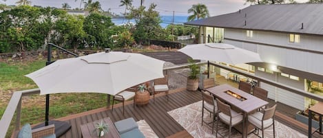 An outdoor patio with a fire pit, seating, and umbrellas.