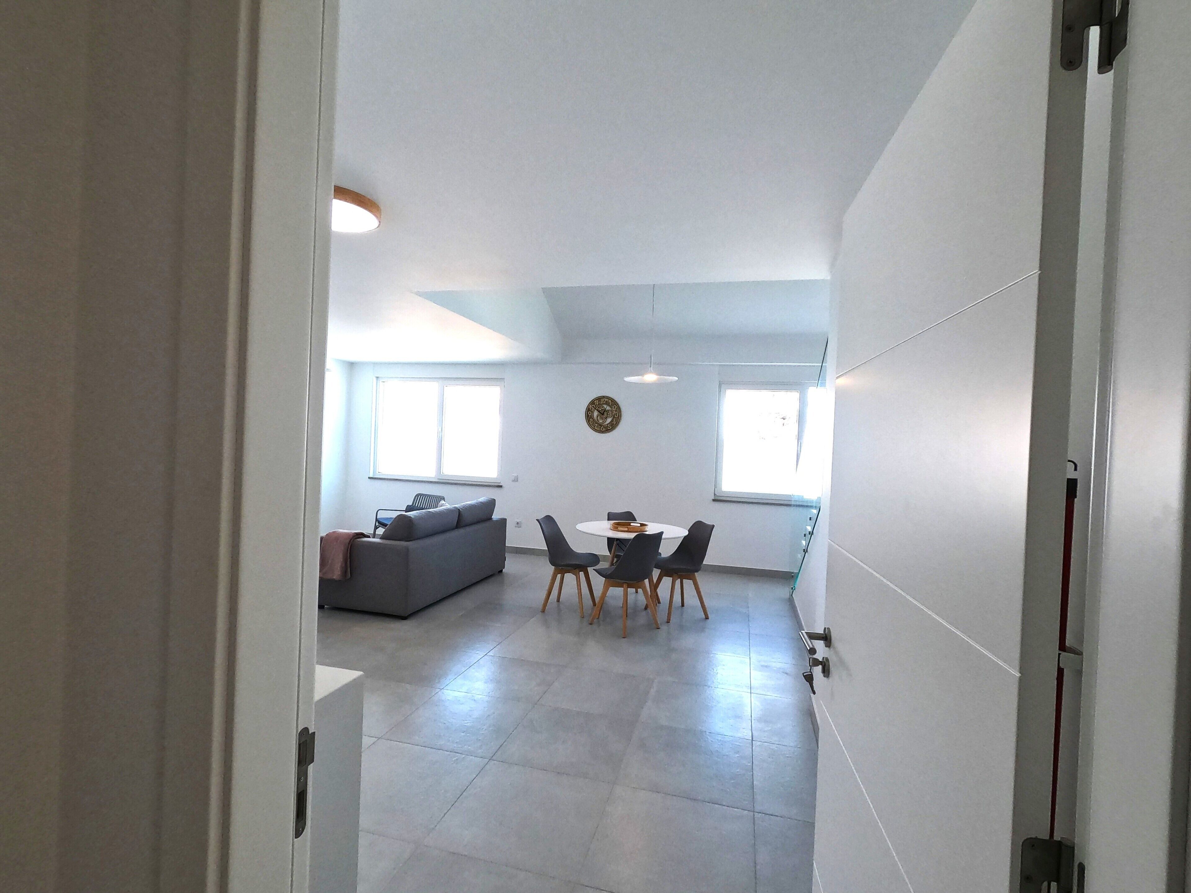 Een modern interieur met een eethoek, een bank en een klok aan de muur.