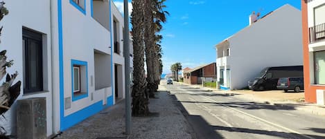 Una strada con edifici, una palma e auto parcheggiate.