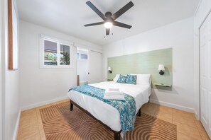 Ein Hotelzimmer mit einem Bett, einem Deckenventilator, einem Fenster und einer Wandlampe.