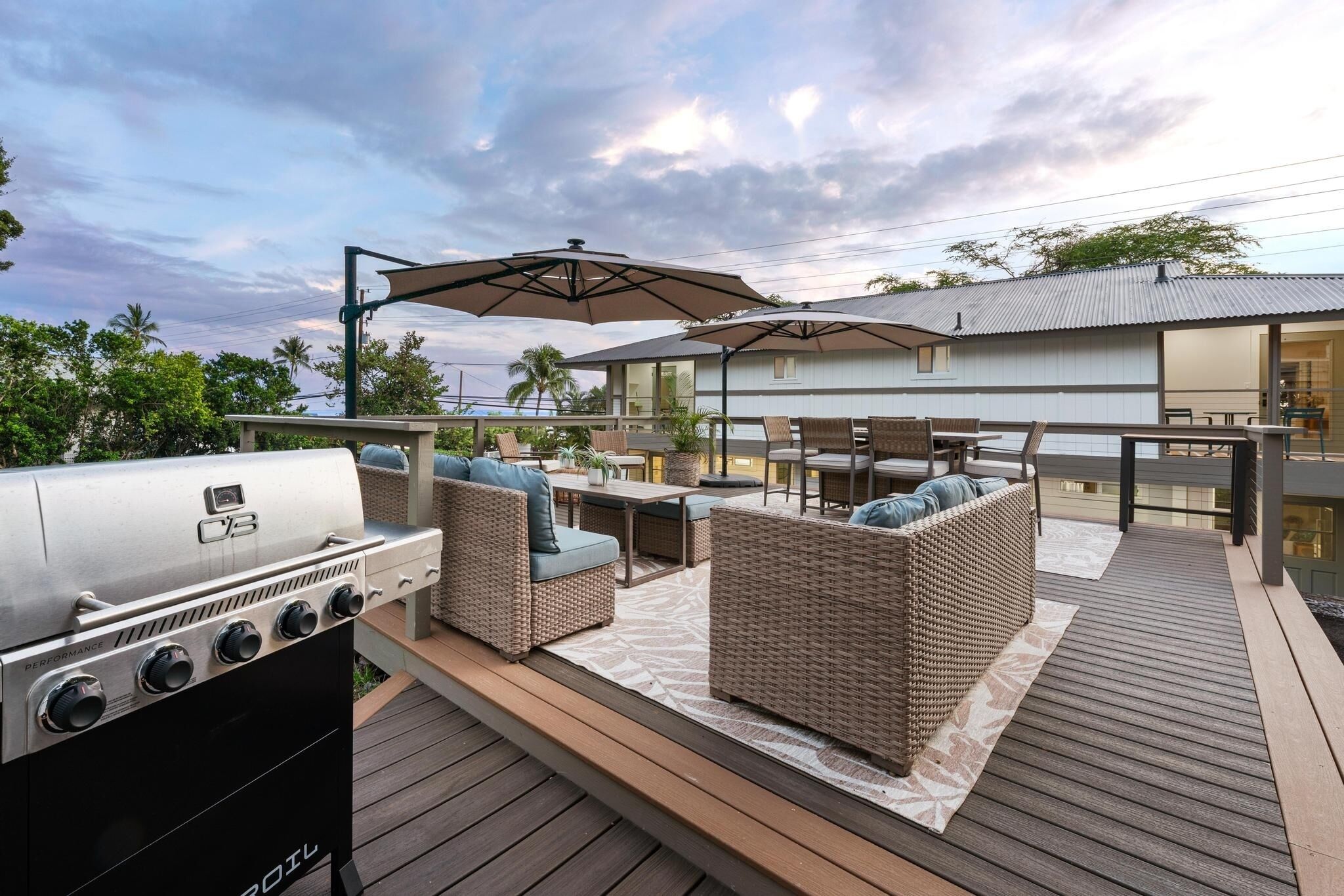 An outdoor patio with a barbecue grill, wicker furniture, and umbrellas.