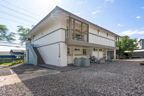 Ein zweistöckiges Gebäude mit Balkon, Treppe und einem Schotterweg.