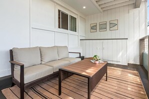 Ein Zimmer mit einer Couch, einem Holztisch und einer Topfpflanze.