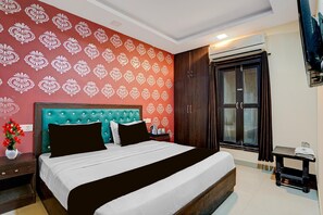 A hotel room with a bed, a nightstand, a dresser, a wardrobe, and an air conditioning unit. - Hotel O IGI Airport Mahipalpur (New Delhi)
