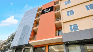 A multi-story hotel building with a prominent orange and grey facade, balconies, and large windows. - Hotel O IGI Airport Mahipalpur (New Delhi)