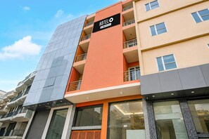 A multi-story hotel building with a prominent orange and grey facade, balconies, and large windows. - Hotel O IGI Airport Mahipalpur (New Delhi)