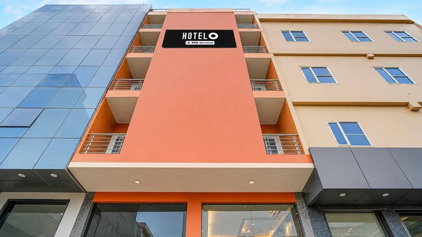 A hotel building with a prominent orange facade, multiple balconies, and a sign indicating it is serviced by OYO. - Hotel O IGI Airport Mahipalpur (New Delhi)
