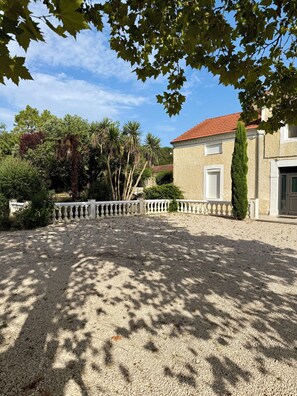 A gravel driveway leading to a building with a red-tiled roof, surrounded by trees and a white fence. - Bed and Breakfast in a renovated farmhouse, swimming pool, peaceful setting, pets welcome, naturist (Lafitole)