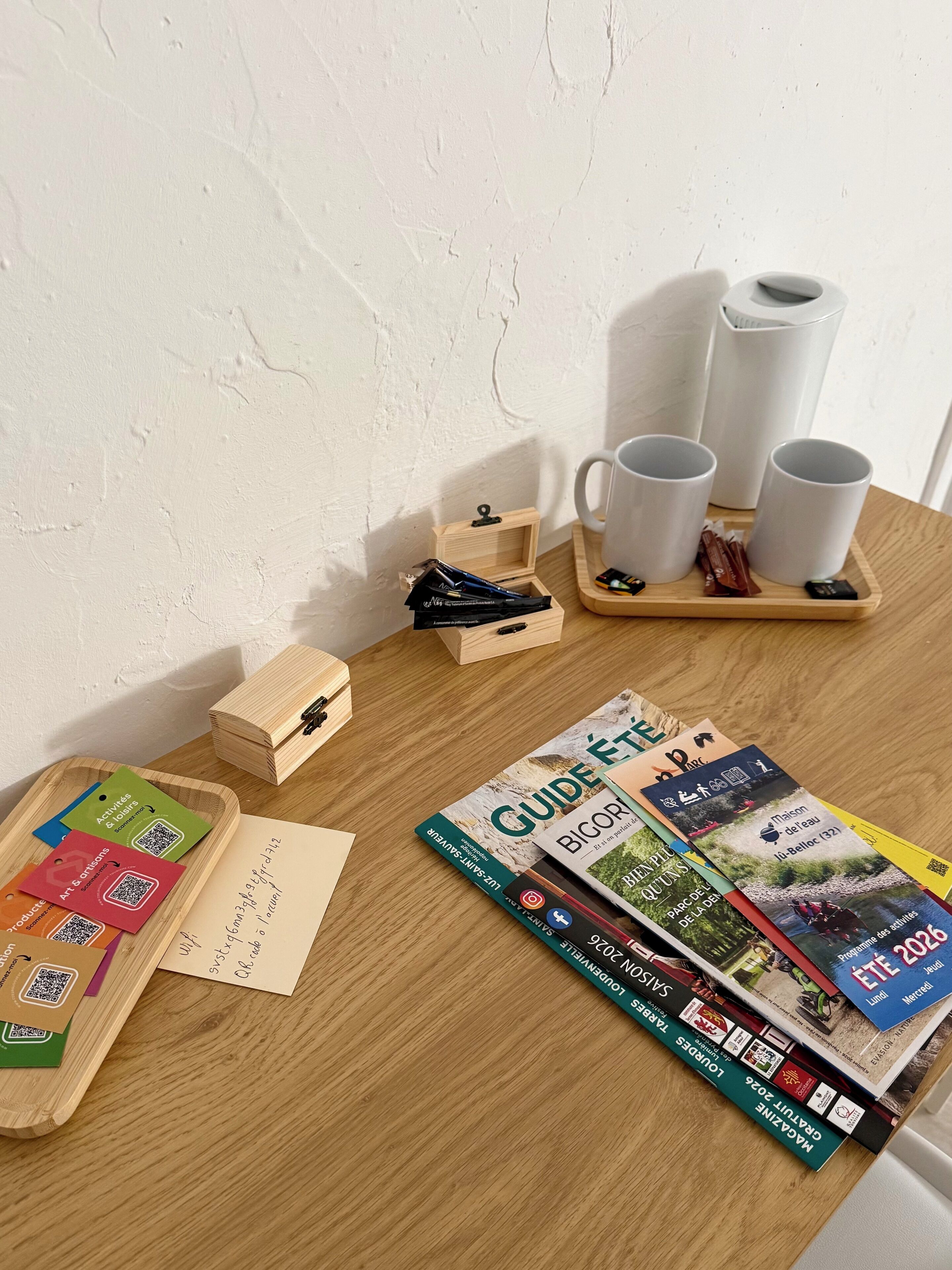 A wooden table with travel brochures, a wooden box, and a tray with mugs and snacks.