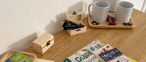 A wooden table with travel brochures, a wooden box, and a tray with mugs and snacks.