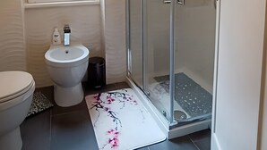 Un bany amb vàter, bidet i plat de dutxa amb envàs de vidre.