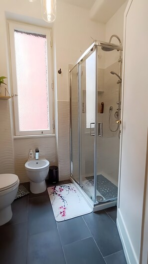 A bathroom with a toilet, bidet, and a glass-enclosed shower stall. - "Verdastro" Apartment with Wi-Fi and Air Conditioning Near Vatican (Rome)