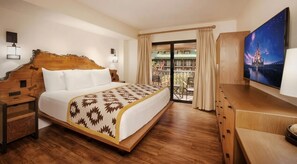 Habitación de hotel con una cama grande, cabecera de madera, balcón con vistas y un televisor en la pared.