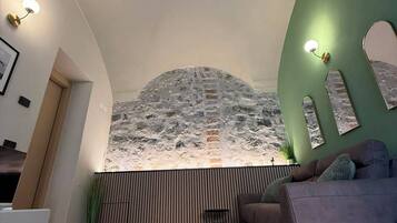 Un interior moderno con techo inclinado, pared de acento verde, alfombra estampada y sofá.