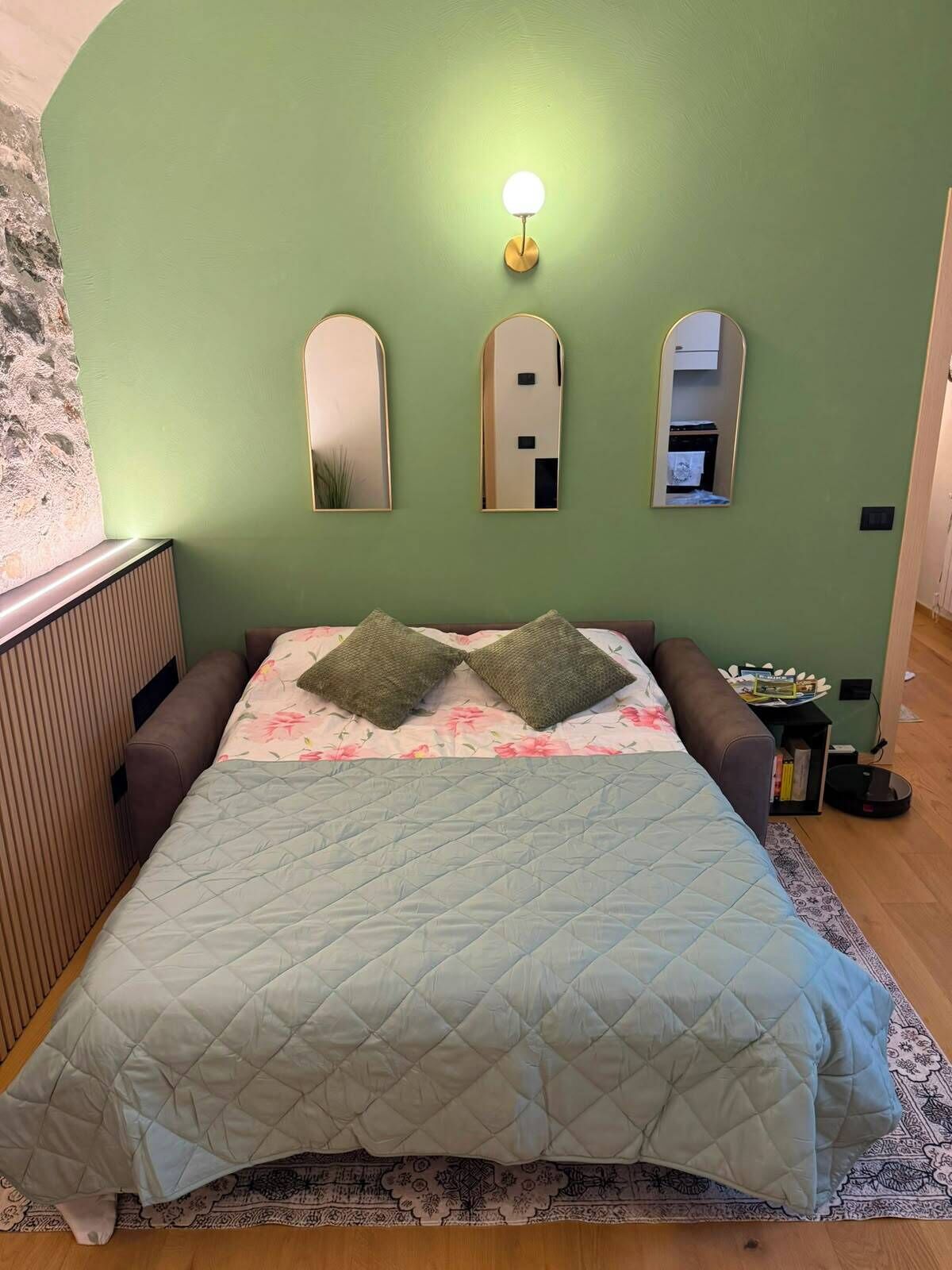 Ein Zimmer mit einem Bett, einem Nachttisch und einer Wandleuchte.