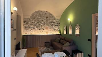 A modern interior with a stone wall feature, a dining area with a marble table, and a green accent wall.