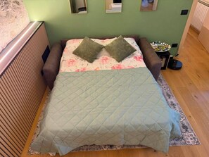 A bed with a quilted cover, two pillows, a floral-patterned pillowcase, and a bedside table with a lamp. - WISTERIA SECRET GARDEN ApartmentHistoric Palace&Private Courtyard (MAX 3 GUESTS) (Lovere)
