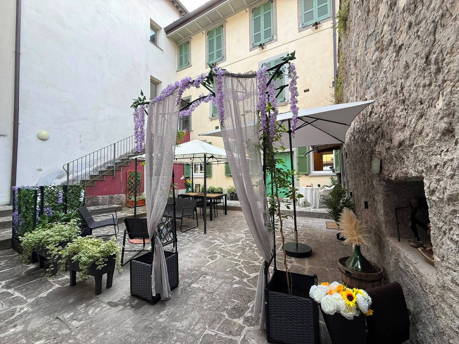 Eine Außenpatio-Terrasse mit Korbmöbeln, einem überdachten Sitzbereich und einem Steinfußboden.