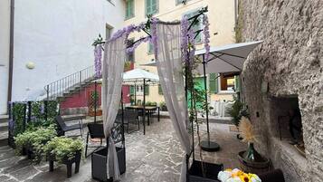 Eine Außenpatio-Terrasse mit Korbmöbeln, einem überdachten Sitzbereich und einem Steinfußboden.