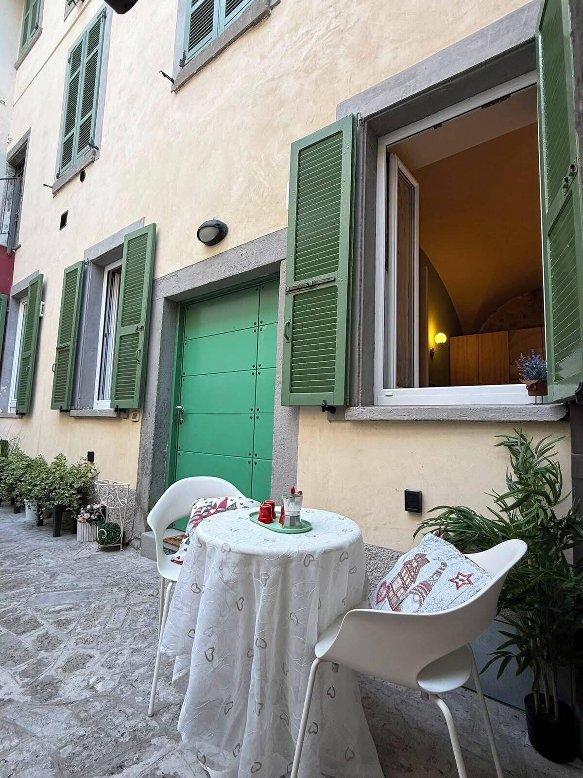 Ein Innenhof mit Tisch und Stühlen, einer grünen Tür und Blumentöpfen.