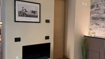 A modern living room with a flat-screen TV, a framed picture on the wall, and a small plant.