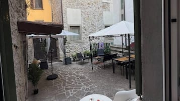 Un patio con mobiliario exterior, suelo de piedra y vistas a edificios vecinos.