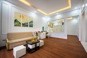 A modern living room with a sofa, coffee table, and a dining area with a chair and a small table. - SoLaRa Trang An Resort - Thap Gia Trang (Tay Hoa Lu)