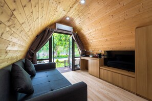 A cozy cabin interior with a sofa, TV, and wooden walls. - SoLaRa Trang An Resort - Thap Gia Trang (Tay Hoa Lu)