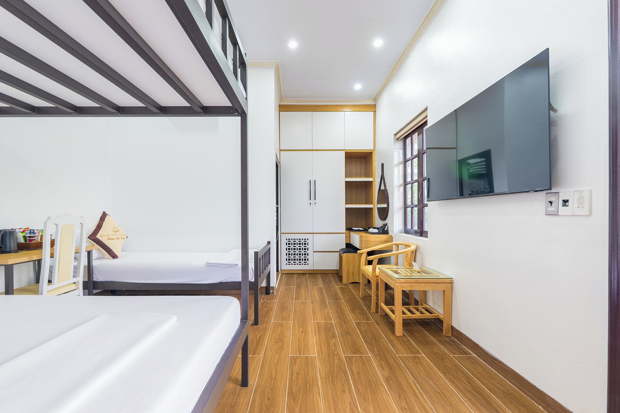 A compact hotel room with a bunk bed, a desk with a chair, a television, and a wardrobe.