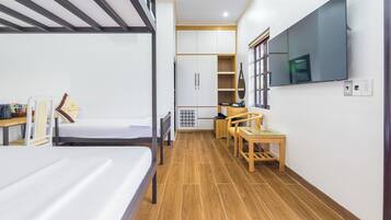 A compact hotel room with a bunk bed, a desk with a chair, a television, and a wardrobe.