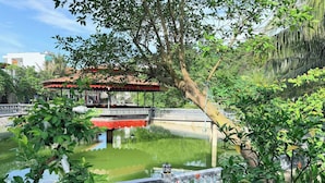 Un jardín tranquilo con un estanque, un puente y un pabellón.