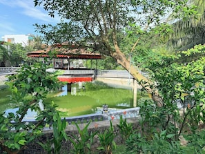 A tranquil garden with a pond, a bridge, and a gazebo.