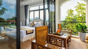 Un dormitorio con un ventanal amplio, un balcón con vistas a zonas verdes y un comedor con mesa y sillas.