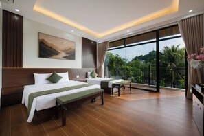 A hotel room with a large bed, a smaller bed, a bench, a desk, and a balcony with a view of greenery. - SoLaRa Trang An Resort - Thap Gia Trang (Tay Hoa Lu)