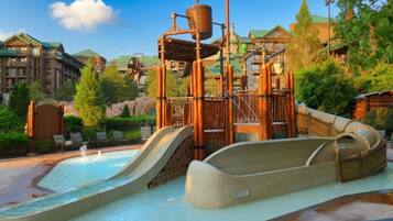 Un parc aquatique doté d’un toboggan et d’une structure de jeux en bois.