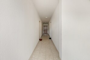 A long, narrow hallway with white walls and a tiled floor.