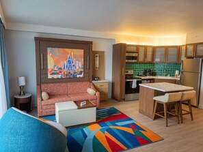 Een moderne woonkamer met een bank, een bijzettafeltje en een kleurrijk vloerkleed.