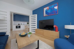 A modern living room with a TV, a red lamp, and a blue abstract painting on the wall. - Stylish Apartment with Air Conditioning | Parking | Close to the City Centre (Warszawa)