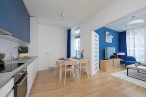A modern kitchen with a built-in oven and a dining area with a wooden table and chairs. - Stylish Apartment with Air Conditioning | Parking | Close to the City Centre (Warszawa)
